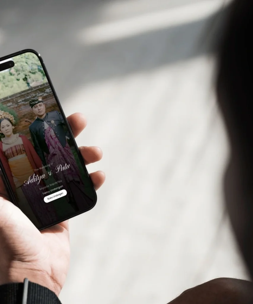 seorang model melihat handphone yang berisi gambar couple prewed di dalam undangan bali cover